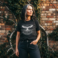 Load image into Gallery viewer, Woman with silver hair wearing the Vintage Black Study No. 21 t-shirt featuring a wings and roots graphic that reads Wings Elevate Roots Ground.