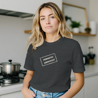 Load image into Gallery viewer, Blonde woman standing in a modern kitchen wearing the Charcoal Grey Vital Threads t-shirt. Features the white "Perfectly Imperfect" distressed box logo.