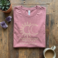 Load image into Gallery viewer, Mauve Pink "Frequencies Matched" tee folded neatly. Celestial design representing friendship and connection.