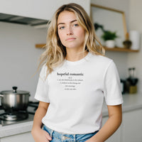Load image into Gallery viewer, Blonde woman in a modern kitchen wearing the White 'Hopeful Romantic' sueded cotton tee. Minimalist wellness apparel for everyday comfort.