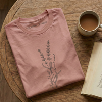 Load image into Gallery viewer, Mauve pink wellness t-shirt folded on a round wooden table. Features a vertical floral branch design with "Hopeful Heart, Quiet Mind" script.