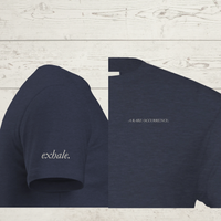 Load image into Gallery viewer, Close-up detail of 'The Exhale' women's premium tee in Navy. Shows the delicate 'A RARE OCCURRENCE' chest typography and 'exhale.' sleeve print on sensory-friendly sueded cotton.