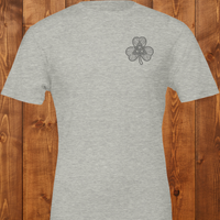 Load image into Gallery viewer, Flatlay of a Heather Grass Green premium t-shirt featuring a minimalist dark charcoal Celtic knot shamrock design on the left chest.