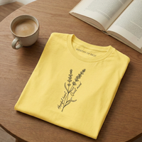 Load image into Gallery viewer, Vital Threads "Worthy of Rest" t-shirt in Soft Yellow. Flat lay on a wooden table with a book and coffee, featuring a lavender flower illustration with "Hopeful Heart, Quiet Mind" text.