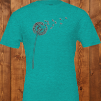 Load image into Gallery viewer, No. 25: The Emergence - Flat lay of a heather blue premium luxury tee featuring a botanical dandelion illustration