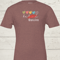 Load image into Gallery viewer, Bella and Canvas Heather Mauve graphic tee featuring red scratch over 'Be Kind' text and distressed 'Genuine' logo."