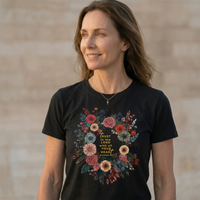 Load image into Gallery viewer, A serene, athletic woman wearing the No. 33 The Calling high-contrast botanical graphic tee in black, paired with a delicate micro-cross necklace, showcasing a quiet luxury aesthetic.