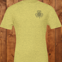 Load image into Gallery viewer, Flatlay of a light heather dust natural t-shirt featuring a dark charcoal Celtic knot shamrock design on the left chest.