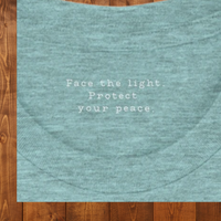 Load image into Gallery viewer, Close-up of the inner collar of the Heather Ice Blue No. 28 The Evolution Premium Luxury Tee, showing the hidden text: Face the light. Protect your peace.