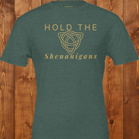 Load image into Gallery viewer, Flat lay mockup of the "Hold the Shenanigans" t-shirt in forest green with gold text and a Celtic knot.