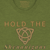 Load image into Gallery viewer, Close-up of a heather green t-shirt featuring a sophisticated gold Celtic knot design and the phrase "Hold the Shenanigans.