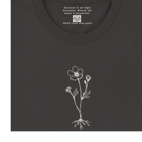 Load image into Gallery viewer, Close-up detail of the 'Survival &amp; Beauty' women's premium graphic tee in Black. Shows the delicate white etched flower and roots design on sensory-friendly sueded cotton, featuring the Vital Threads Clothing Signature  Message, and  inner neck inspirational quote.