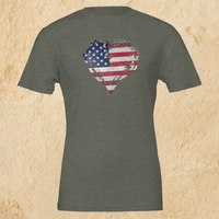 Load image into Gallery viewer, Flat lay of the Heather Military Green Deep Roots, Steady Heart shirt on a tan background, showing the full distressed American flag heart graphic across the chest.