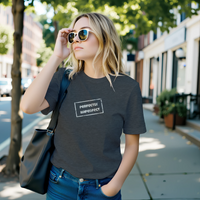 Load image into Gallery viewer, Woman walking down a city street wearing the Dark Grey "Perfectly Imperfect" tee with sunglasses and a shoulder bag.