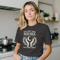 Load image into Gallery viewer, Close-up kitchen lifestyle presentation demonstrating the effortless drape and premium ring-spun cotton architecture of a dark vintage graphic tee built for the rule-breaker.