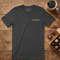 Load image into Gallery viewer, Dark Heather Grey "Soulful" graphic tee folded on wood with a box of chocolates. Minimalist design aesthetic.