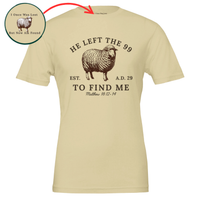 Load image into Gallery viewer, Soft Cream He Left the 99 to Find Me shirt, flat front view showing the engraved sheep with "He left the 99" arched above, "To find me" and Matthew 18:12-14 below, with an inset close-up of the inner collar message.
