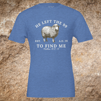 Load image into Gallery viewer, Flat lay of the front of the He Left the 99 to Find Me shirt in Heather Blue, showing the full arched sheep graphic and Matthew 18:12-14 reference.