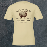Load image into Gallery viewer, Flat lay of the front of the He Left the 99 to Find Me shirt in Warm Cream, showing the full arched sheep graphic and Matthew 18:12-14 reference.