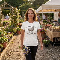 Load image into Gallery viewer, Woman holding a bouquet of wildflowers at an outdoor farmers market wearing the He Left the 99 to Find Me shirt in White, front sheep graphic visible.