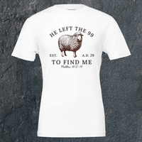 Load image into Gallery viewer, Flat lay of the front of the He Left the 99 to Find Me shirt in White, showing the full arched sheep graphic and Matthew 18:12-14 reference.