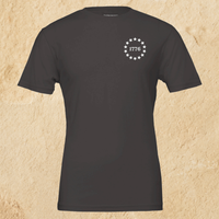 Load image into Gallery viewer, Front flat lay of the Land of the Free, Home of the Brave shirt in Vintage Black, showing the 1776 star-circle badge on the left chest.