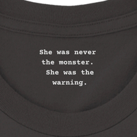 Load image into Gallery viewer, Inner collar reading She was never the monster She was the warning in white typewriter text