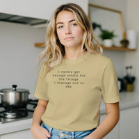 Load image into Gallery viewer, Woman in a bright kitchen setting wearing the No 29 Unspoken Word minimalist tee in cream