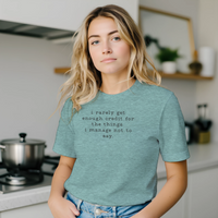 Load image into Gallery viewer, Woman in a bright kitchen setting wearing the No 29 Unspoken Word minimalist tee in heather teal