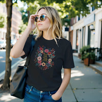 Load image into Gallery viewer, A modern minimalist woman walking outdoors wearing the No. 33 The Calling premium luxury tee in black, featuring a vintage botanical floral graphic and styling an effortless everyday uniform.