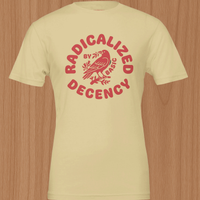 Load image into Gallery viewer, Front view mockup of the No. 35 Radicalized By Basic Decency shirt in Soft Cream — circular raspberry red block-letter graphic surrounding a detailed line-art crow on a premium side-seamed cotton tee.
