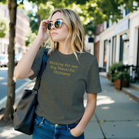 Load image into Gallery viewer, Someone in motion on a city street wearing the No. 36 Big Beautiful Obituary shirt in Heather Military Green, carrying an unstructured leather tote as part of a curated lifestyle.