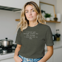 Load image into Gallery viewer, Woman in a bright kitchen setting wearing the No 29 Unspoken Word minimalist tee in olive green.