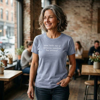 Load image into Gallery viewer, Woman smiling in a warm café setting — Your Little Ray of Sarcastic Sunshine Has Arrived heather blue premium graphic tee by Vital Threads.