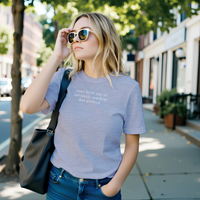 Load image into Gallery viewer, Woman mid-movement on a tree-lined street — Your Little Ray of Sarcastic Sunshine Has Arrived heather blue premium graphic tee by Vital Threads.