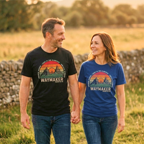 Man wearing the Waymaker shirt in Black holding hands with a woman wearing the Waymaker shirt in Heather True Royal, outdoors in an open field.