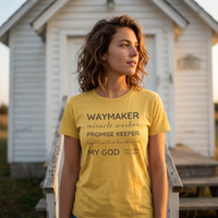 Load image into Gallery viewer, Woman wearing the Heather Yellow Gold Waymaker, Promise Keeper shirt, standing in front of a small white country church at golden hour.

