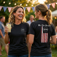 Load image into Gallery viewer, Two women in black We The People premium tees displaying the 1776 Betsy Ross star circle front graphic and We The People distressed flag back print side by side