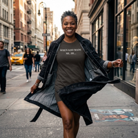 Load image into Gallery viewer, Woman twirling with an open denim jacket on a city sidewalk, wearing the When God Made Me shirt in Vintage Black with the "When God Made Me, He..." front graphic.