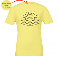 Load image into Gallery viewer, Yellow You Are The Light shirt, flat front view: a half sun rising over water with You Are The Light in serif inside the sun, and Matthew 5:14 below.
